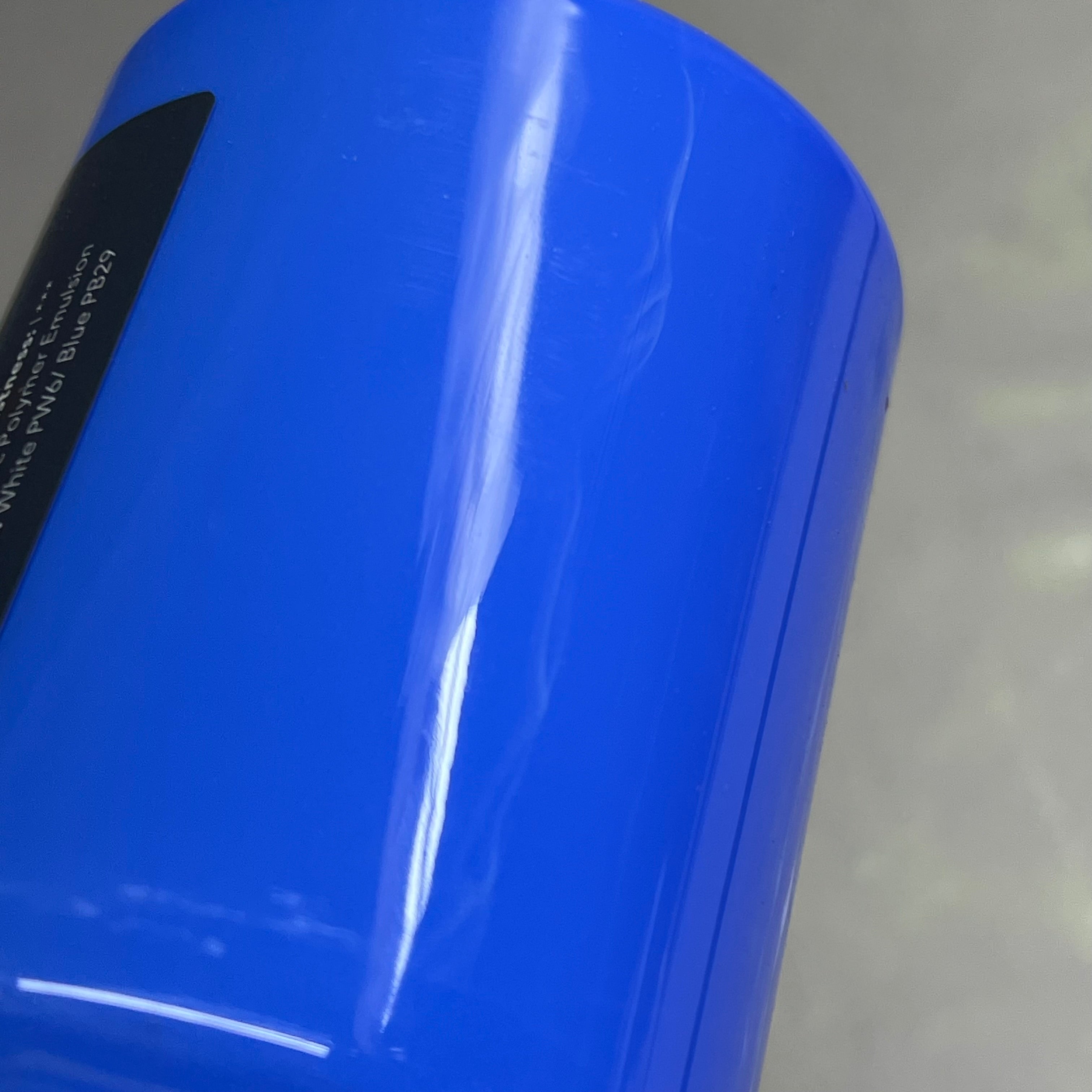 Upside down bottom view of Master's Touch Cobalt Blue acrylic paint bottle showing blue paint color through transparent plastic container with label on gray background