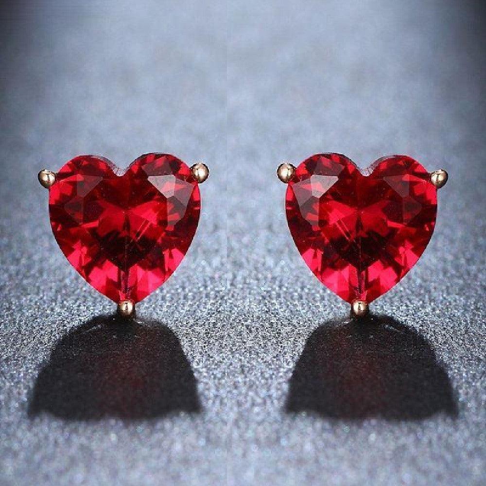 Close-up of red faceted water diamond heart-shaped gemstone stud earrings on gray background showing Valentine's Day jewelry