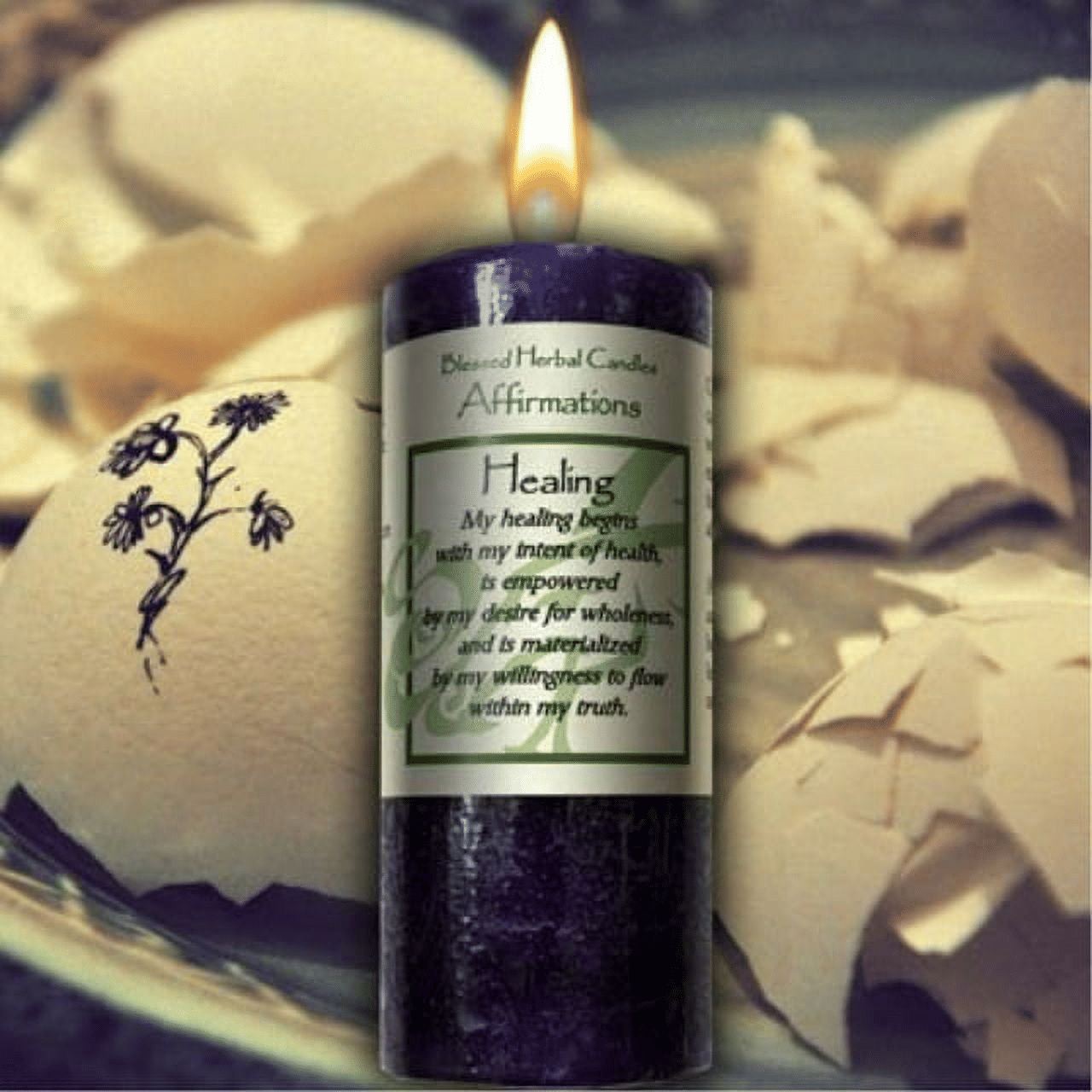 Purple Coventry Creations Healing Affirmations candle with label on broken eggshell background with purple wax flower drawing on shell piece