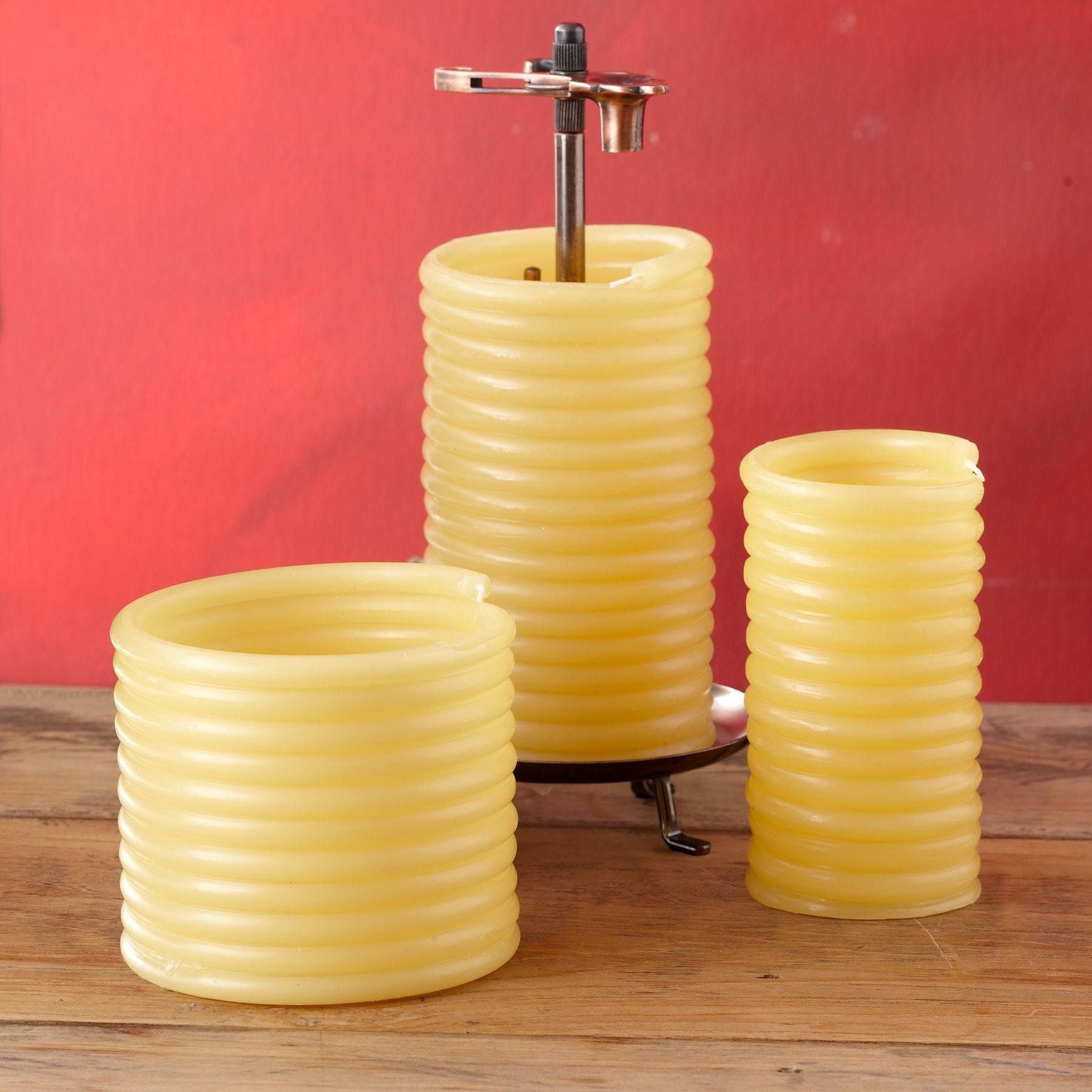 Three Eclipse coiled beeswax candles in beige on wooden surface with red background