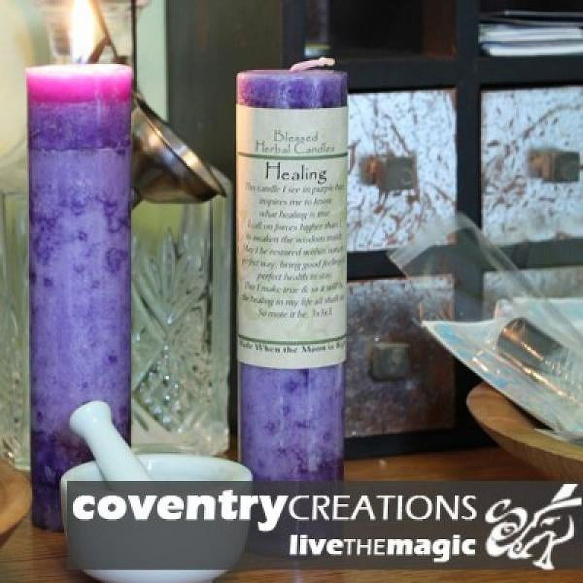 Purple Coventry Creations candle with Healing Affirmations label on table in old style apothecary setting