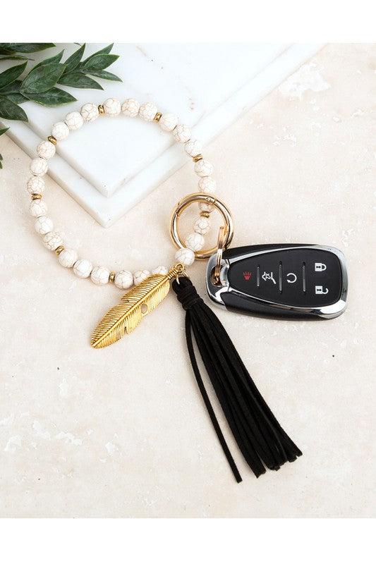 Cream stone bangle key ring bracelet with black suede tassel and feather charm - boho hands-free key holder jewelry