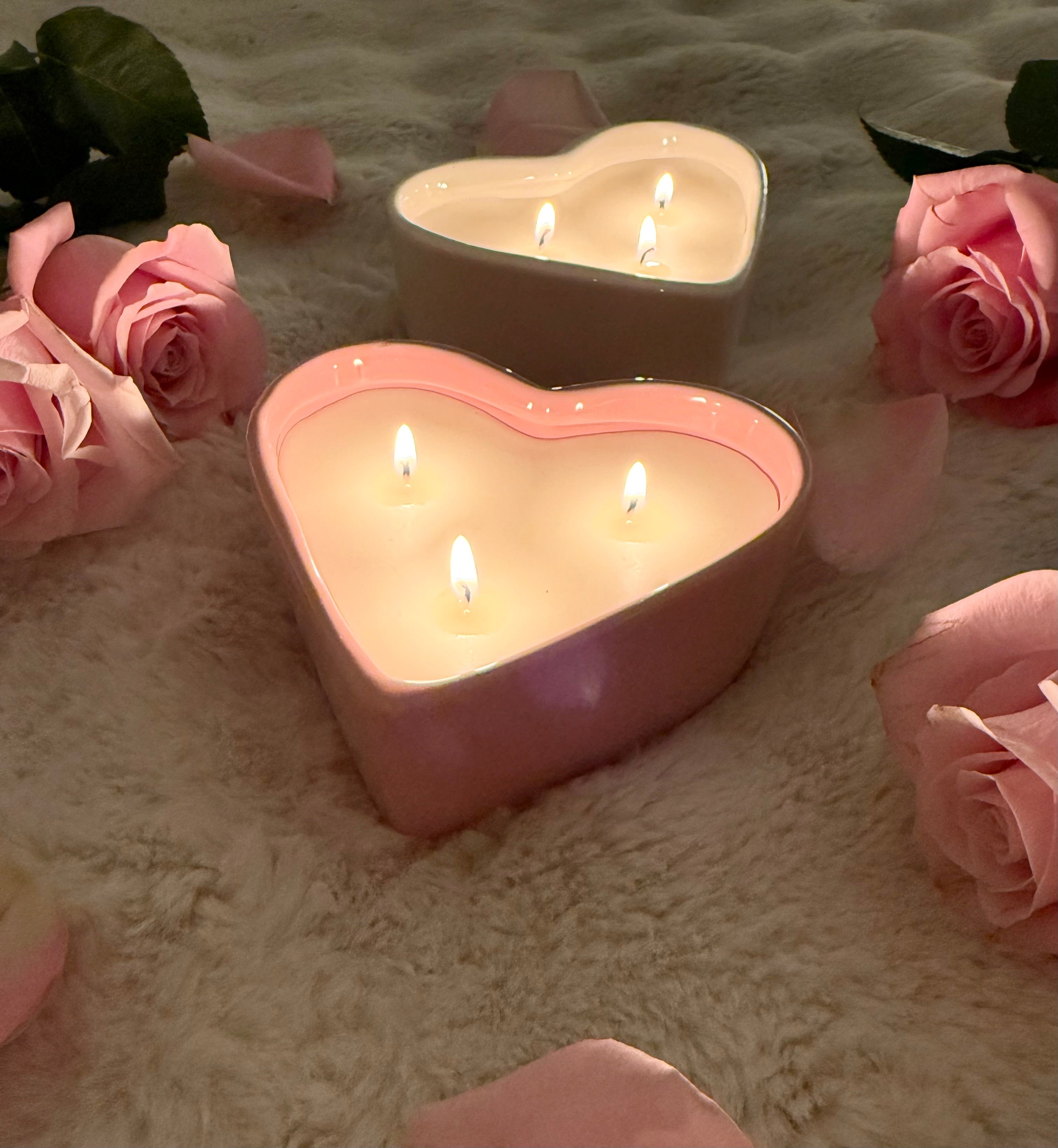 Heart-shaped lit candles glowing in the dark with pink roses on soft surface - romantic ambiance Valentine's Day candle
