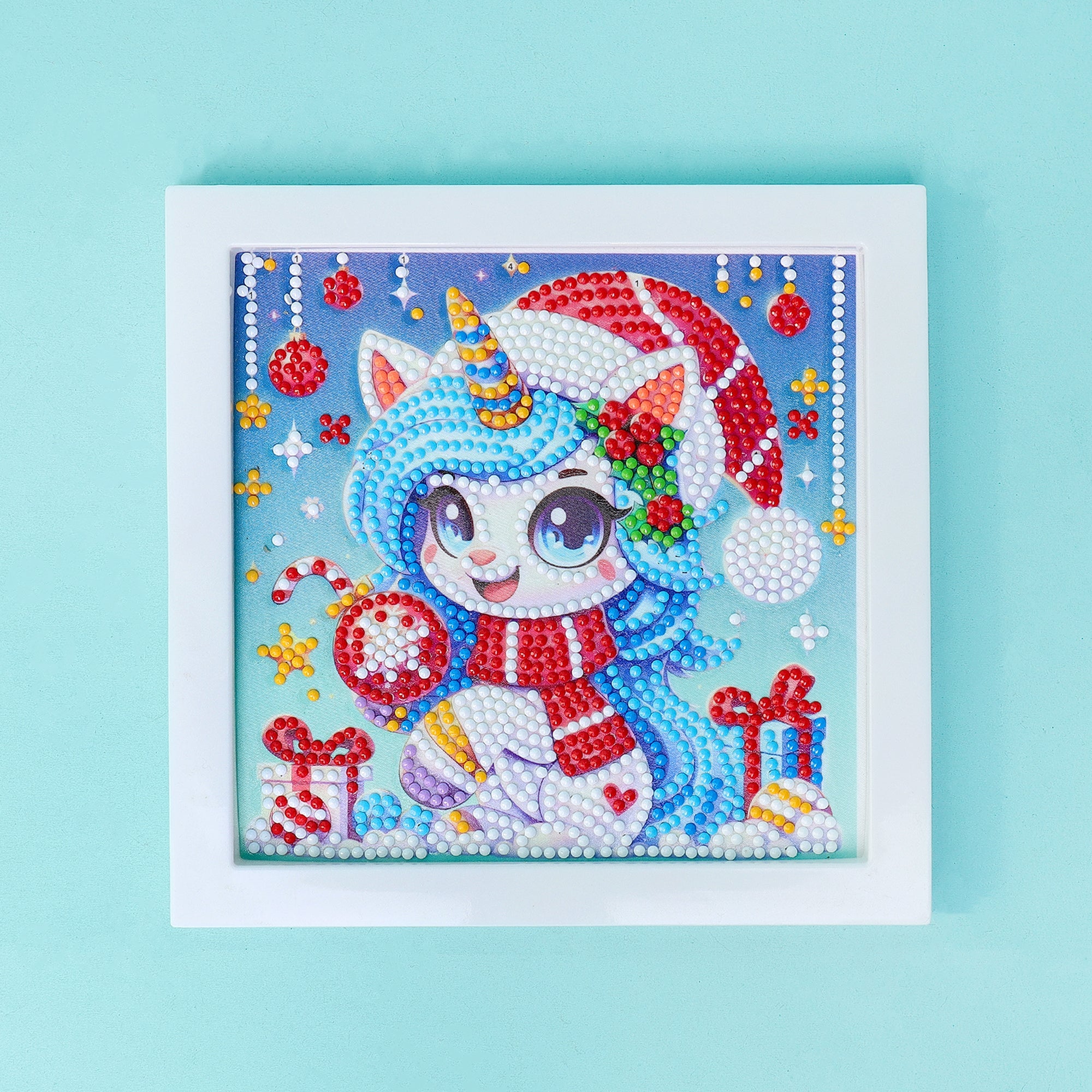 Diamond painting of a cartoon unicorn with blue hair and a Santa hat and Christmas decorations on a light blue background