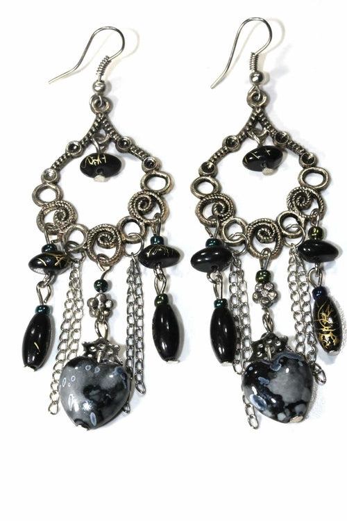 Pair of black marbled bead dangle earrings with silver scroll work and chains on white background