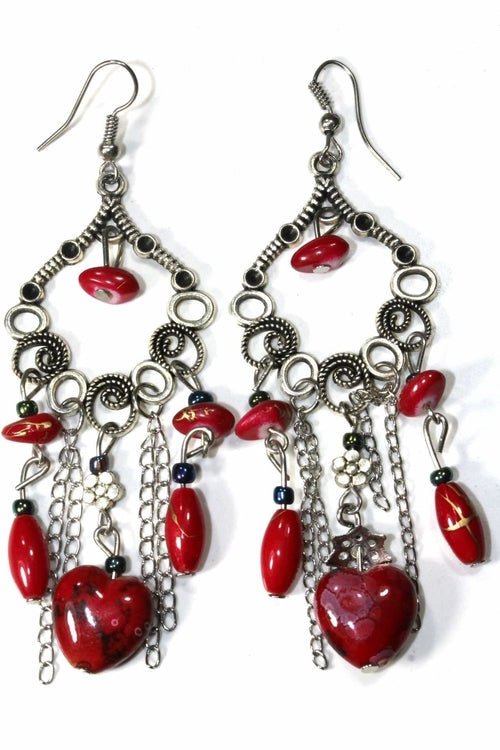 Pair of red marbled bead dangle earrings with silver scroll work and chains on white background
