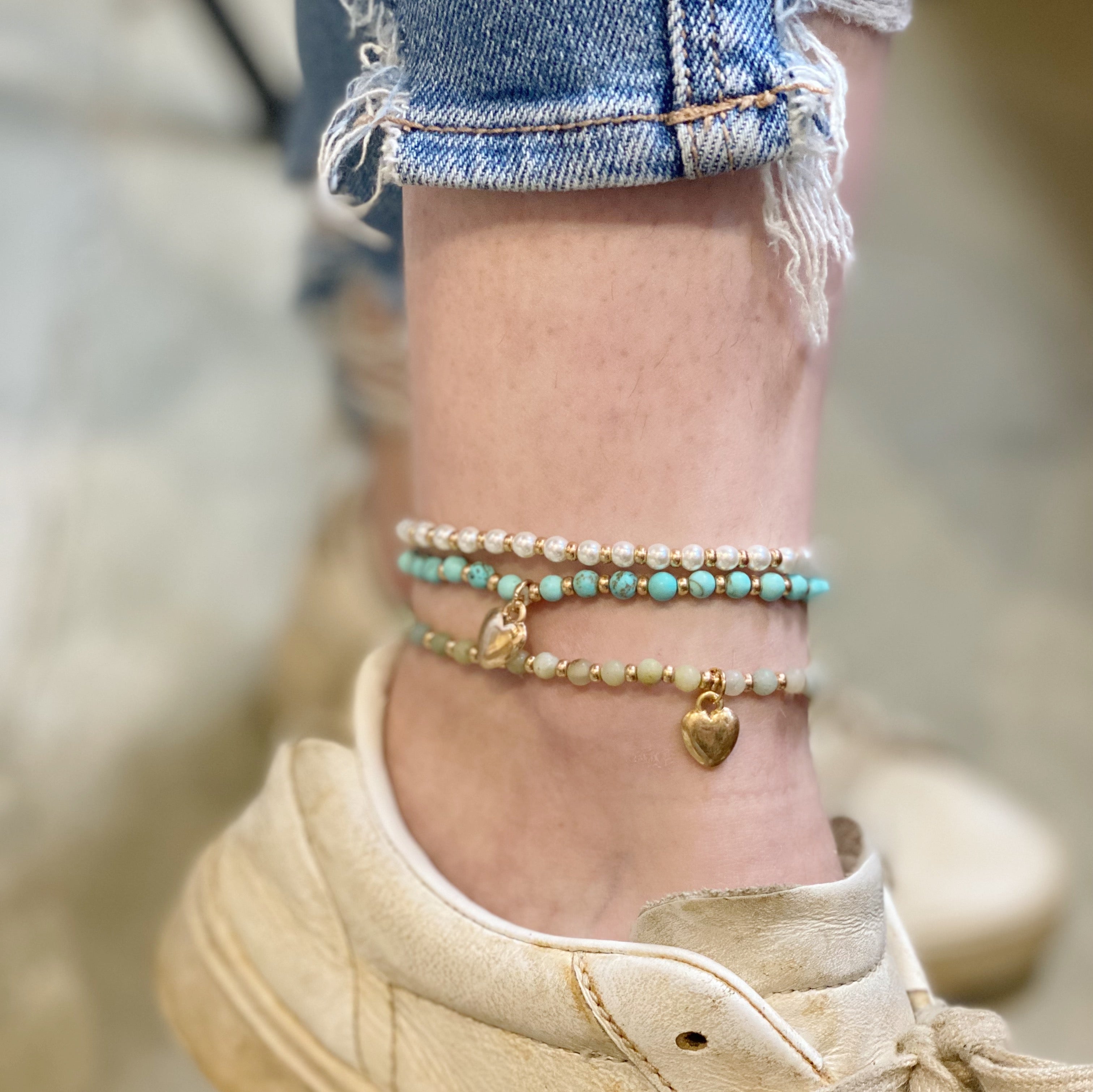 Ankle with three layered stone bead anklets and sneaker on blurred background - boho stacked anklet styling