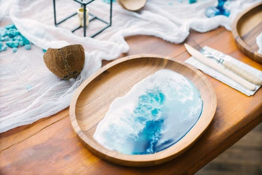 Wooden tray with a blue resin design on a wooden table