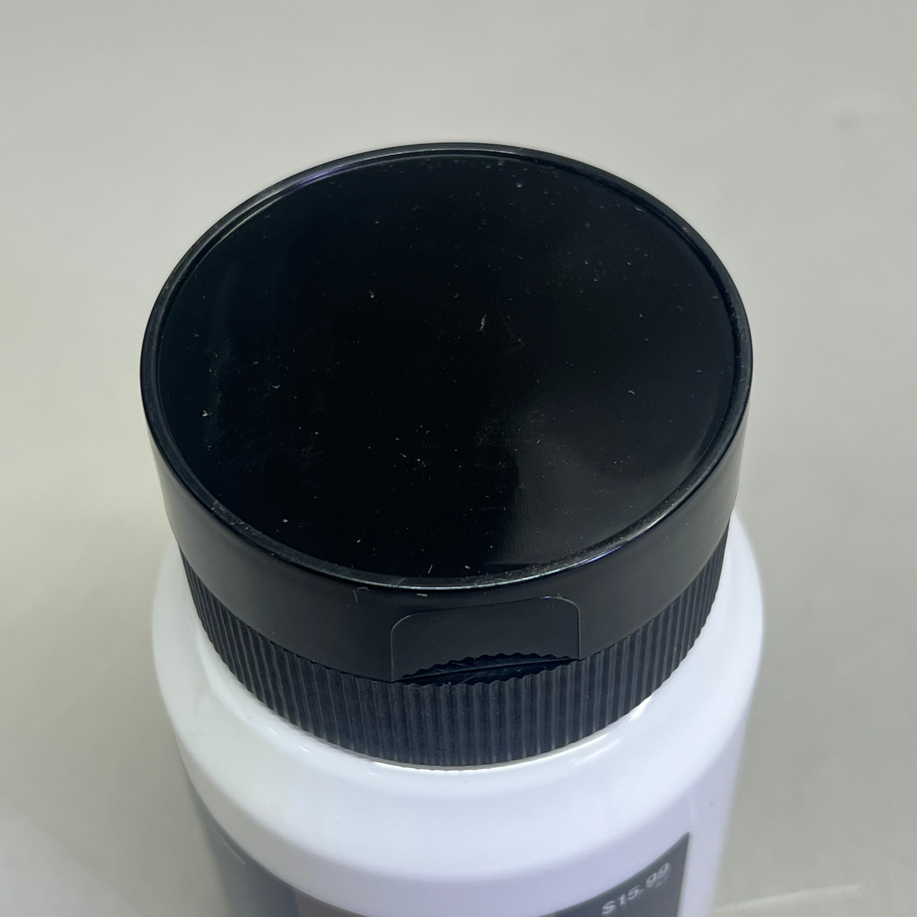 Close up of black bottle cap on Master's Touch titanium white acrylic paint bottle on white background