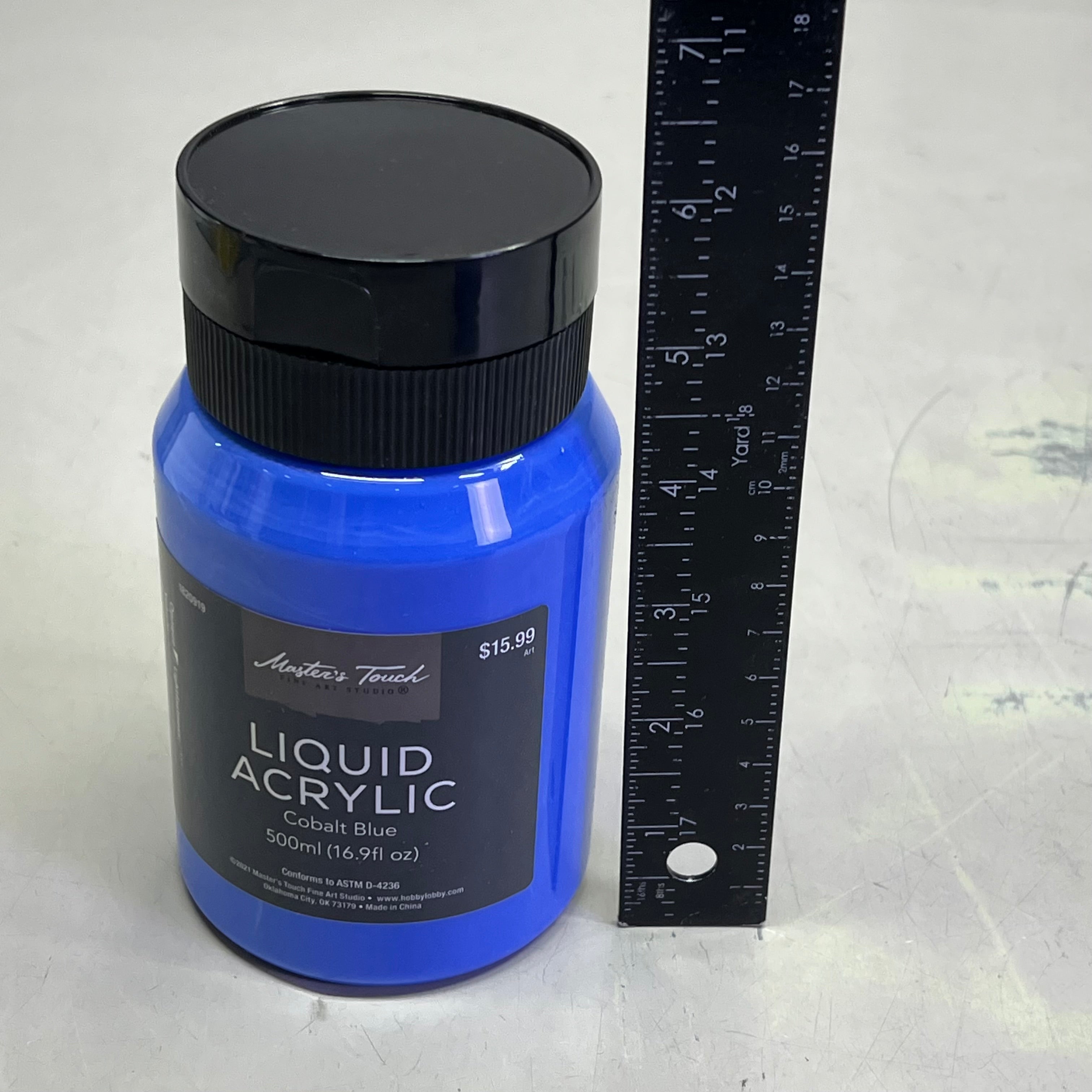 Master's Touch Liquid Acrylic Cobalt Blue paint bottle with black lid next to ruler showing size comparison on white background - 16.9 oz blue acrylic paint