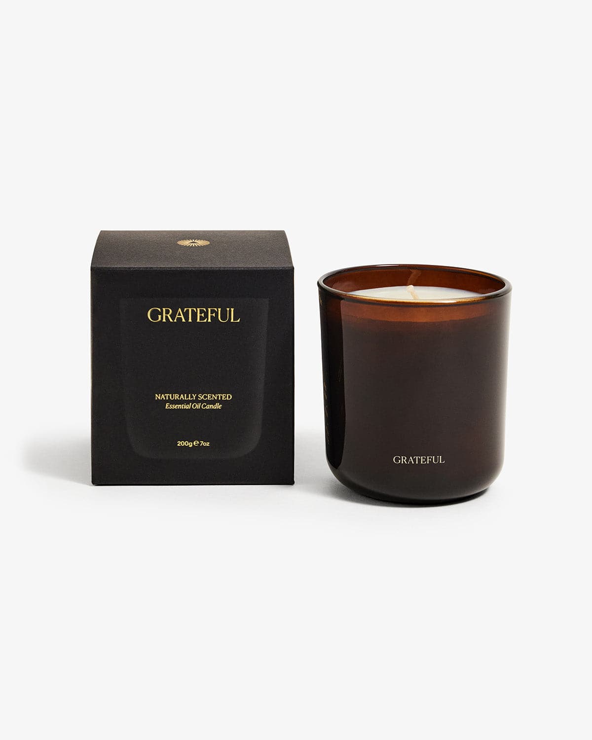 Grateful aromatherapy candle in brown glass container next to black box packaging on white background - pure essential oil soy candle
