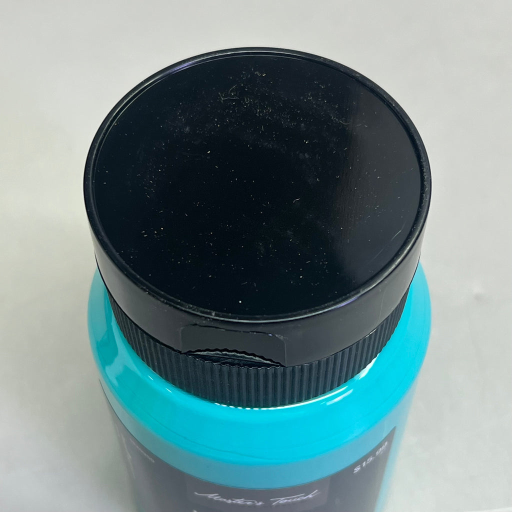 Close-up top view of Master's Touch Viridian acrylic paint bottle with black lid showing blue-green paint color through transparent plastic container on white background