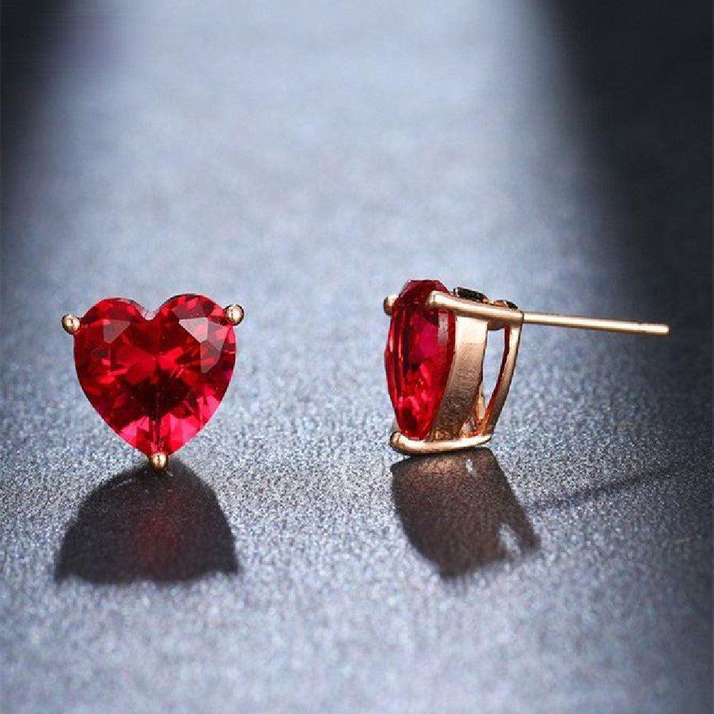 Front and side views of red faceted water diamond heart earrings on lighted black surface showing sparkle and dimension