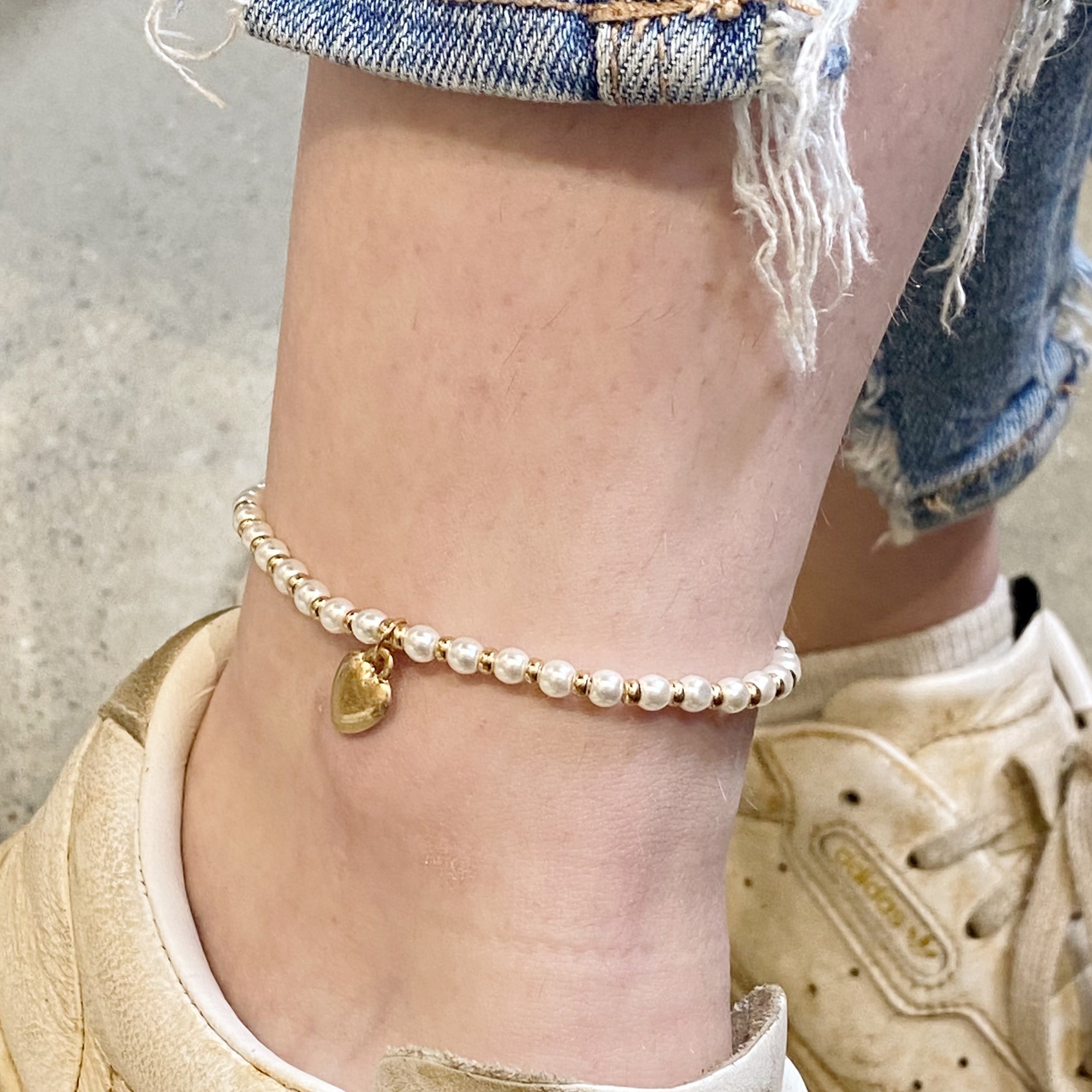 Ankle wearing pearl beaded anklet with gold heart charm and sneakers - natural stone Valentine's Day jewelry styling