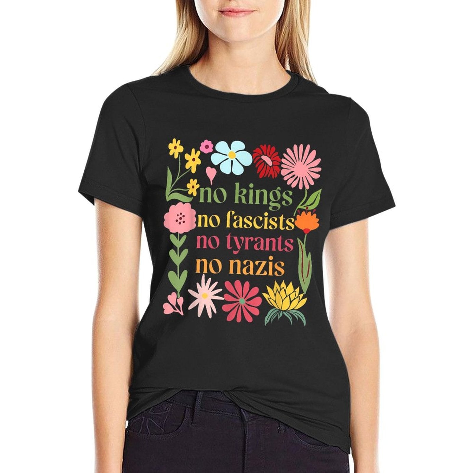 Woman wearing black stretchy t-shirt with colorful floral design surrounding "no kings no fascists no tyrants no nazis" text on white background
