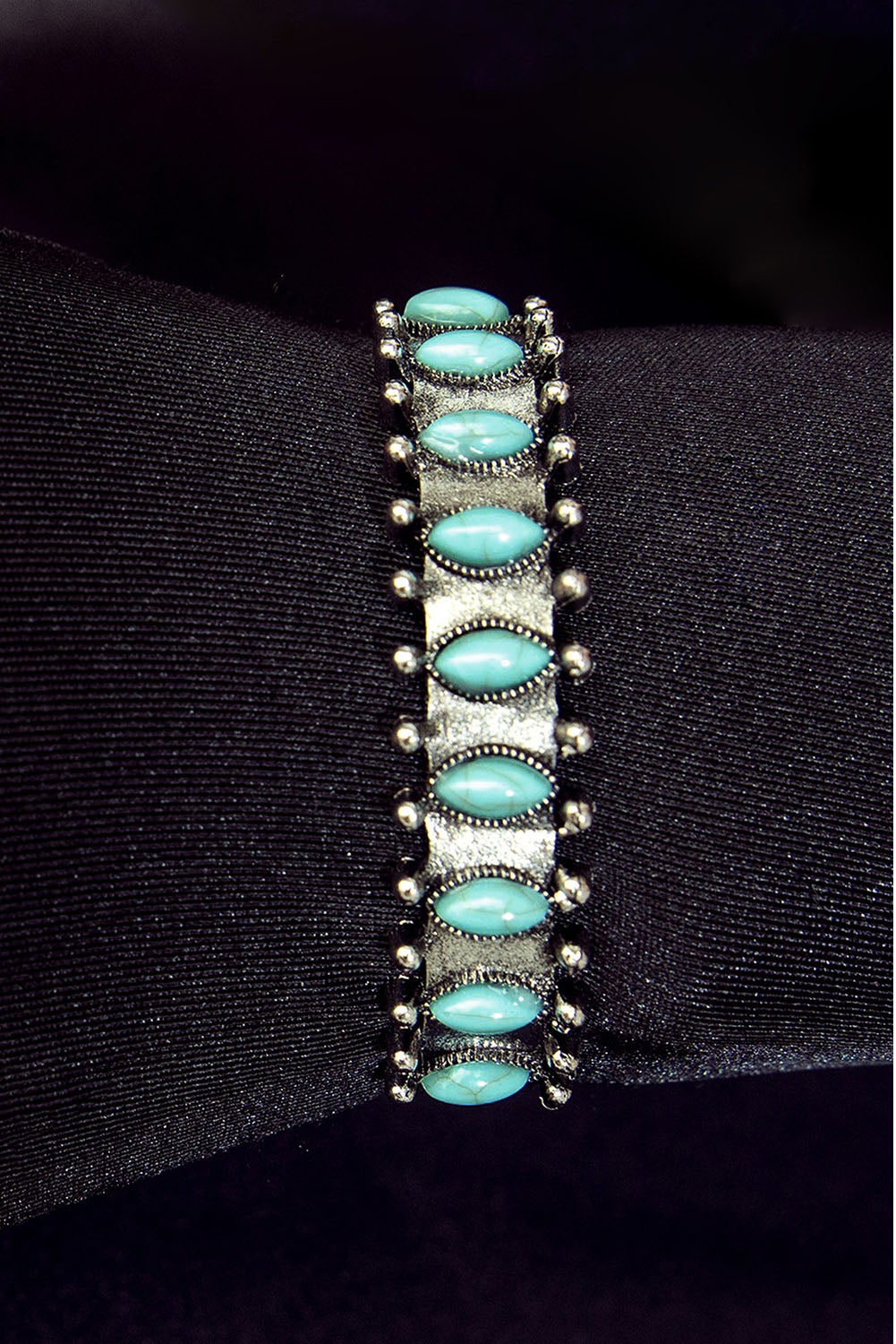 Silver open cuff bracelet with turquoise gemstones - top view on black background