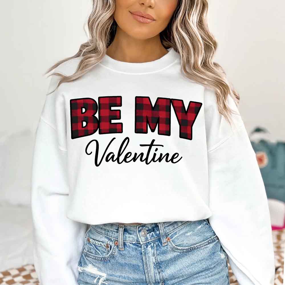 Person wearing white Be My Valentine crewneck sweatshirt with red buffalo plaid text - Valentine's Day outfit