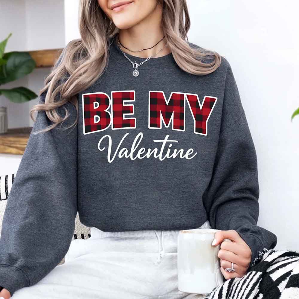 Person wearing dark gray Be My Valentine buffalo plaid crewneck sweatshirt holding mug - cozy Valentine's Day