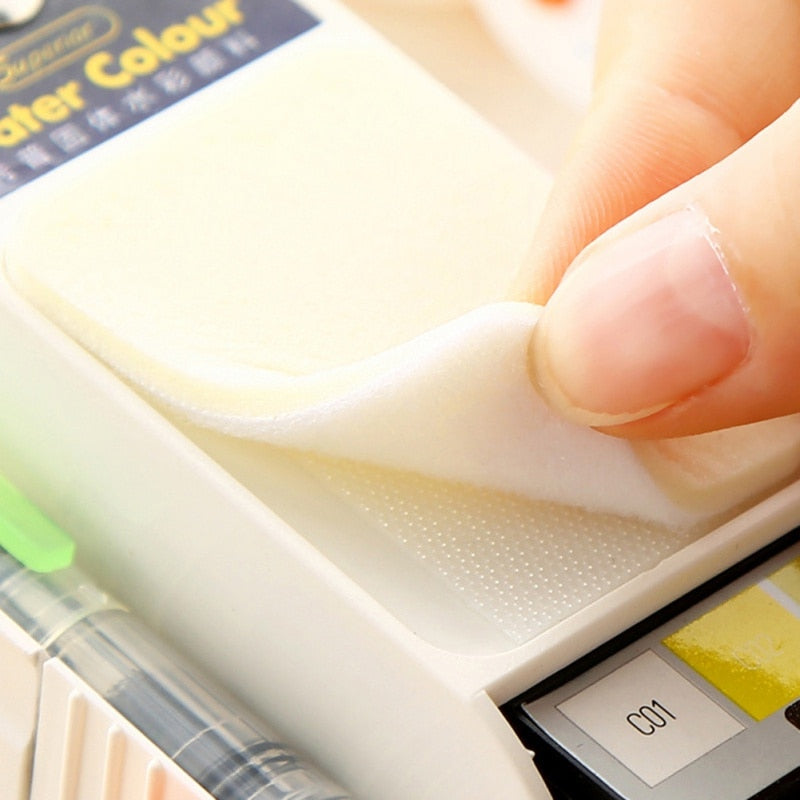 Close up of hand lifting sponge with Water Colour text and water brush - foldable watercolor paint set detail