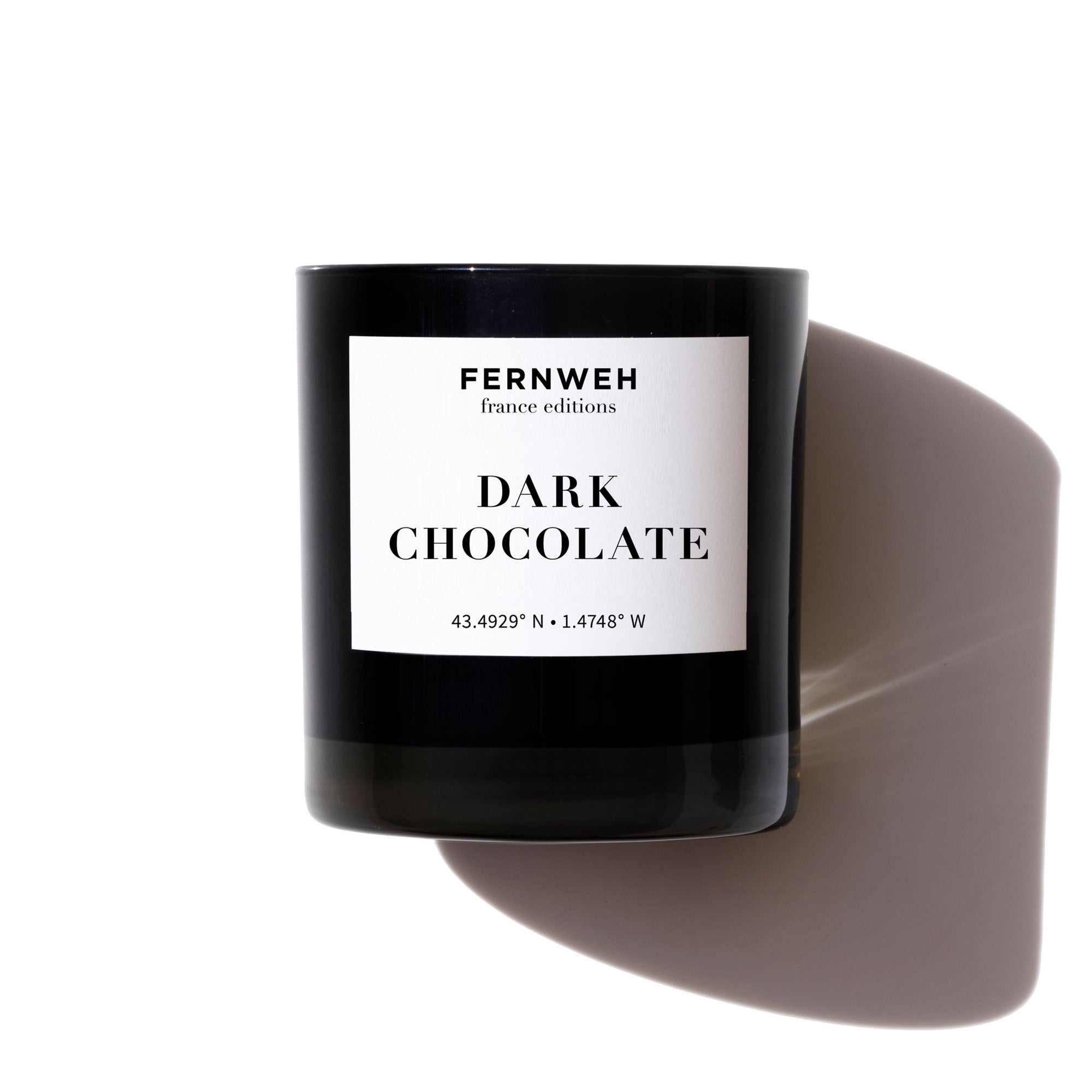 Fernweh Dark Chocolate scented soy candle in black jar with white label on white background
