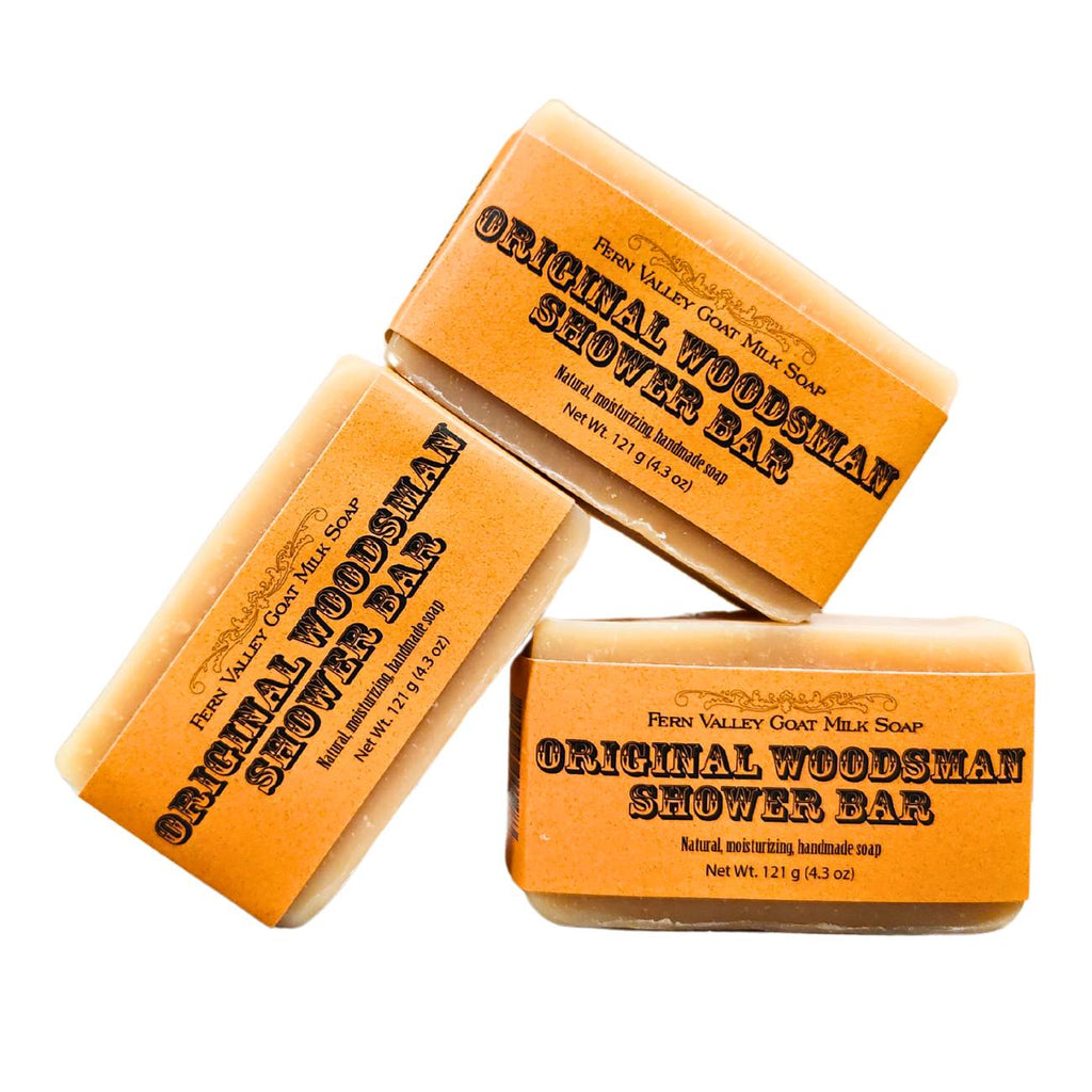 Three stacked bars of Original Woodsman Shower Bar soap on white background