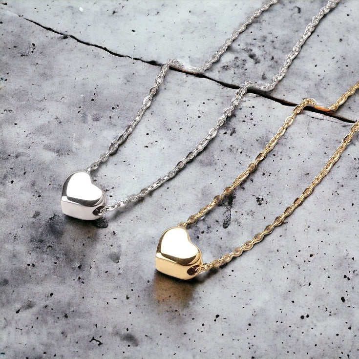 Front and side view of gold and silver puffed heart charm anklets against concrete background - tarnish-free Valentine's gift