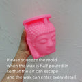 Pink Buddha-shaped silicone mold held by hand against plain background with molding instructions - candle making mold tutorial