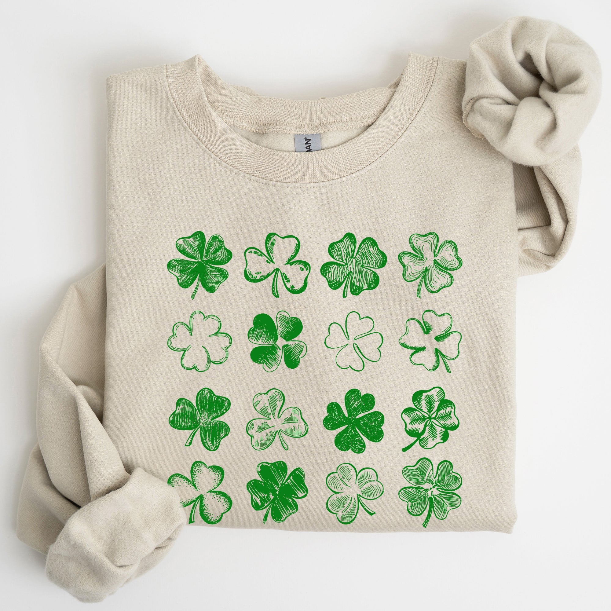 Beige sweatshirt with green shamrock patterns on a white background
