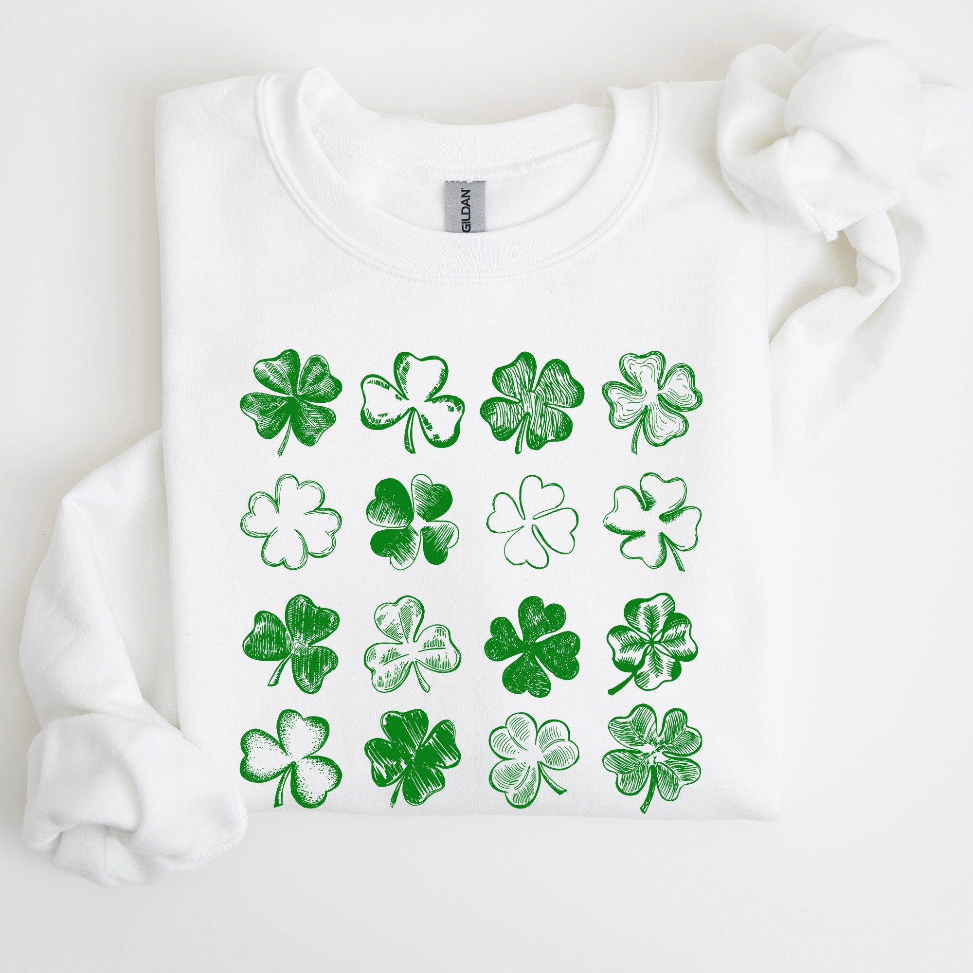 White sweatshirt with green shamrock patterns on a white background