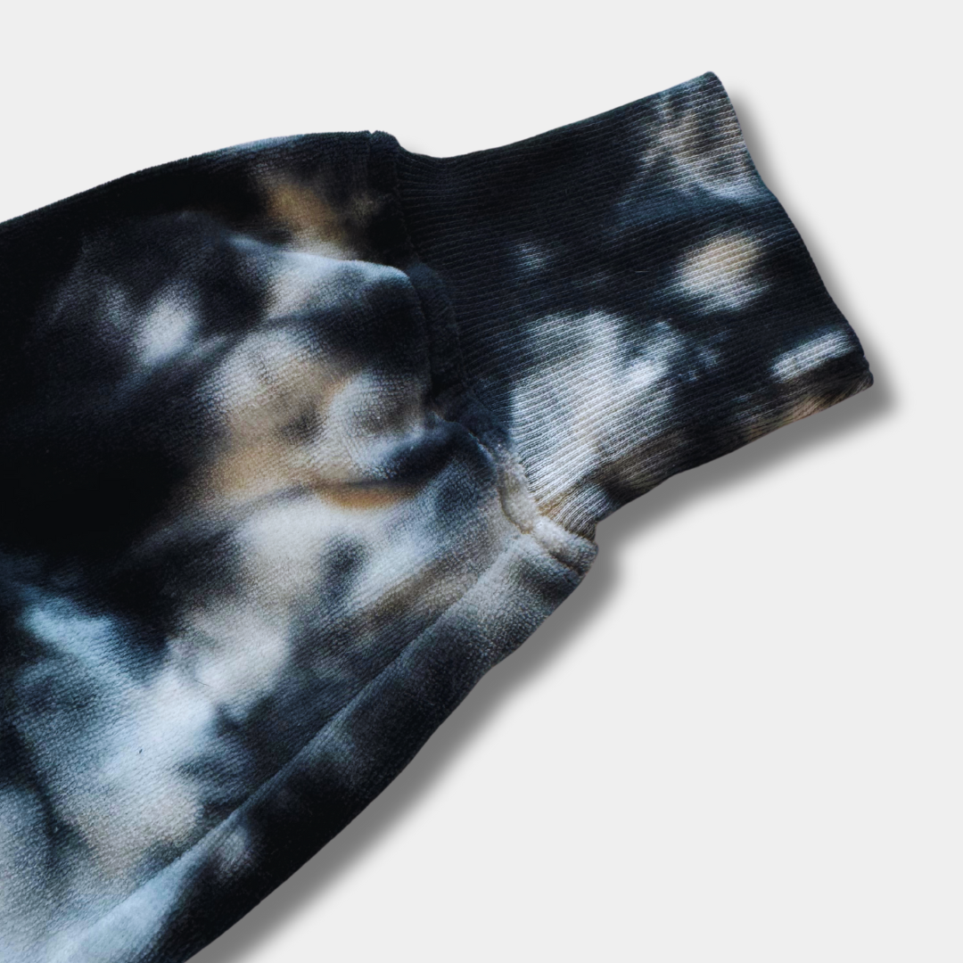 Closeup of black and white tie-dye patterned fabric sleeve cuff on light gray background - midnight velvet crop pullover detail