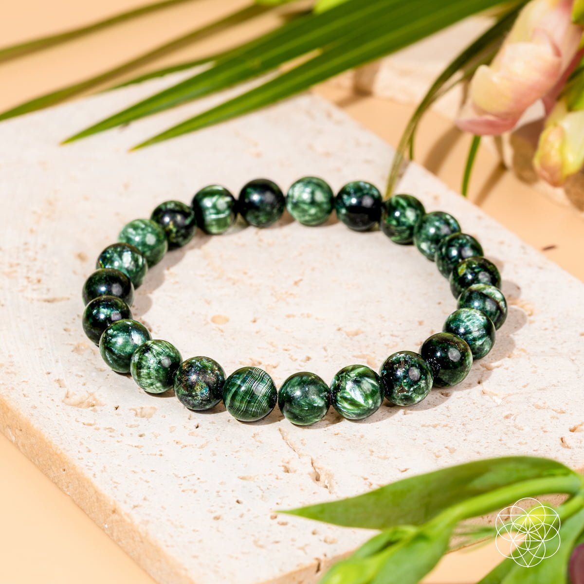 Green seraphinite beaded bracelet on light stone surface with green leaves - angel energy crystal jewelry