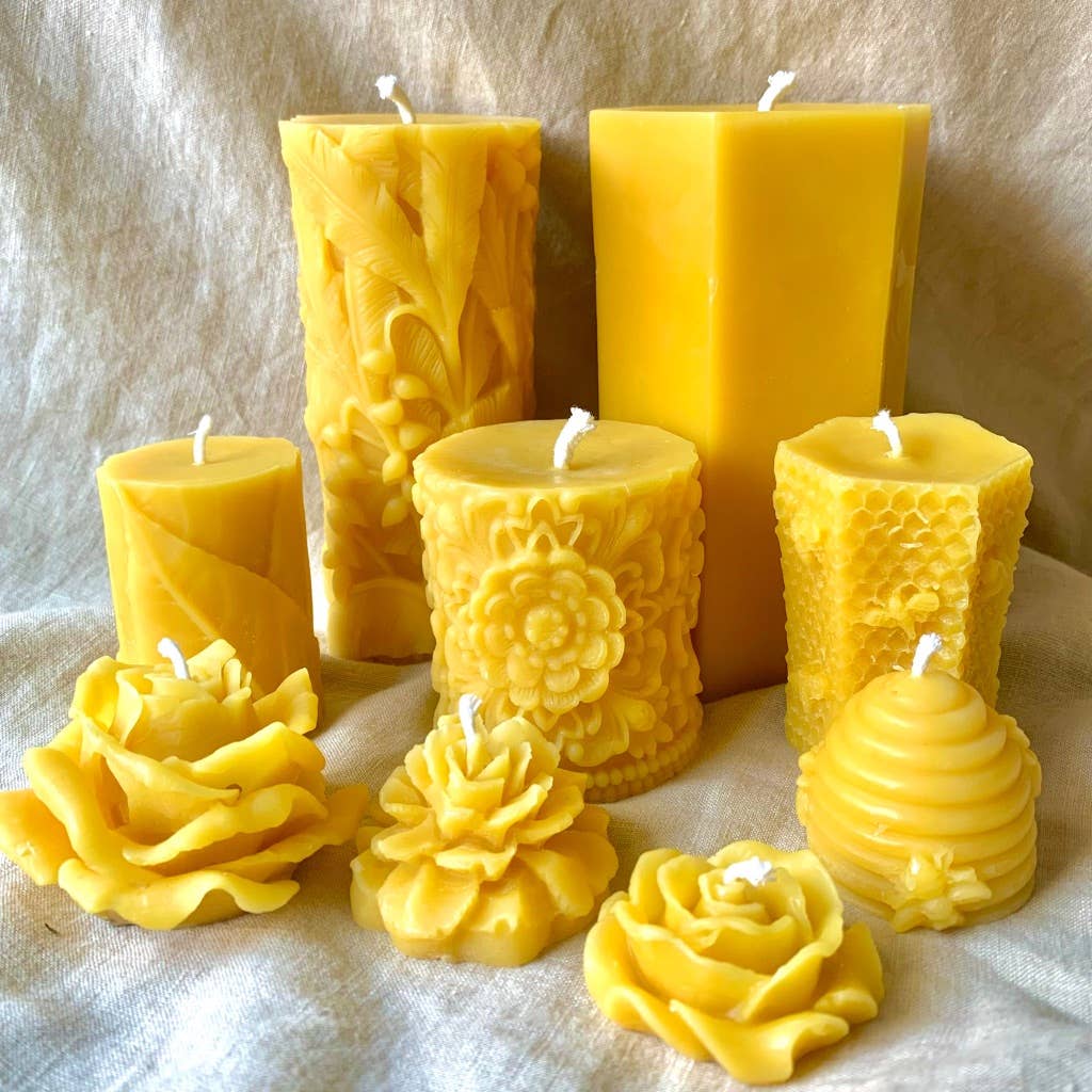Set of various yellow beeswax pillar candles with intricate mandala designs on textured surface