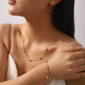 Woman wearing dainty 18K gold-plated heart jewelry set with necklace bracelet and crystal heart stud earrings on neutral background - Valentine's Day gift
