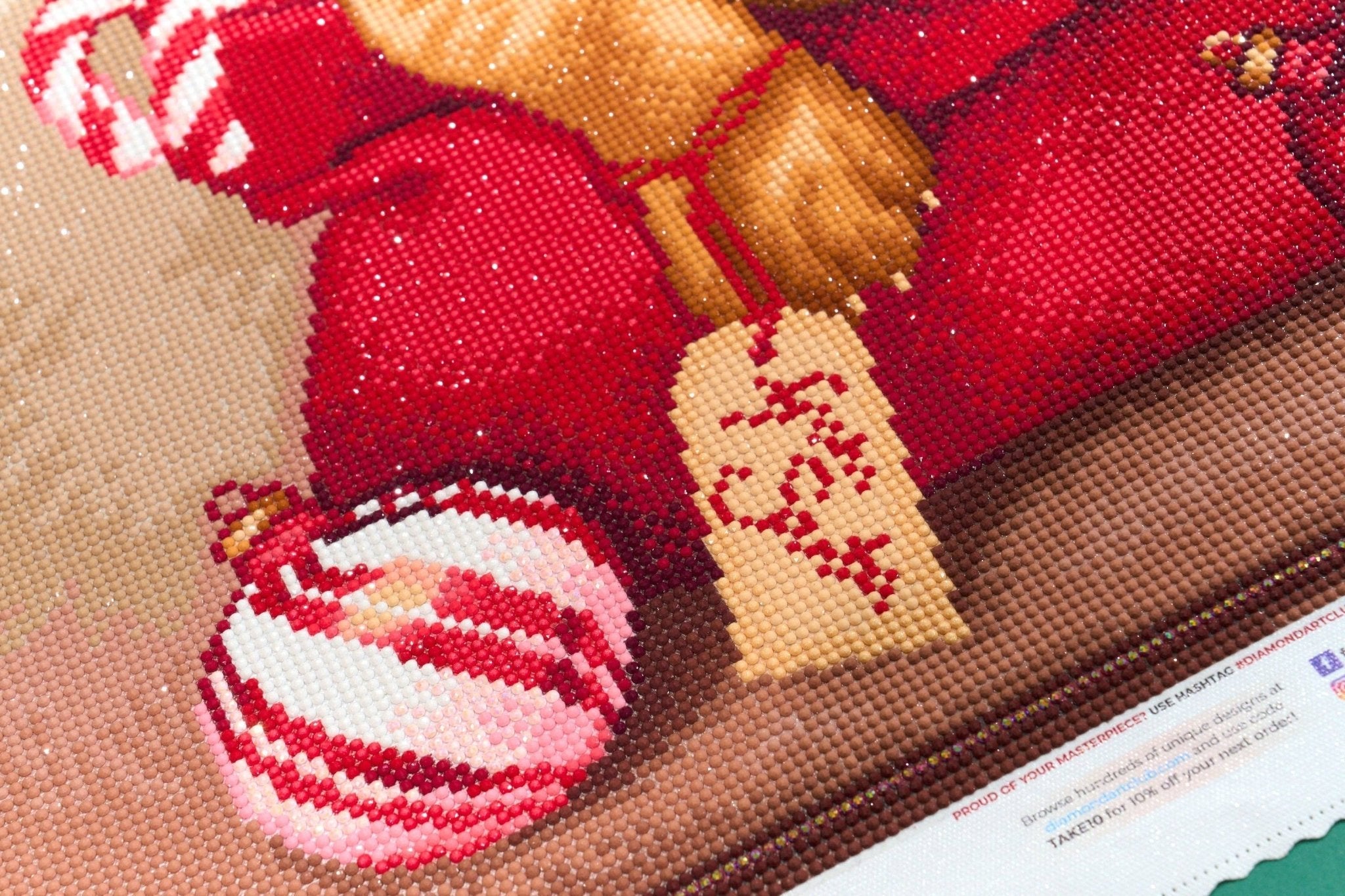 Closeup diamond art design of a Christmas stocking with candy cane and Christmas ornament on canvas.