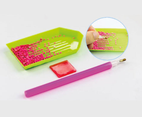 Pink and green diamond art tools with closeup of pink gemstones on a white background