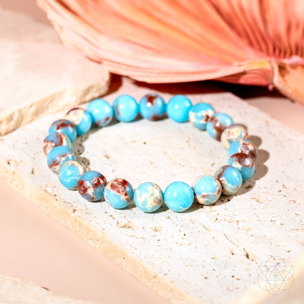 Mottled turquoise aqua terra jasper beaded bracelet on pink background with seashell - closeup view