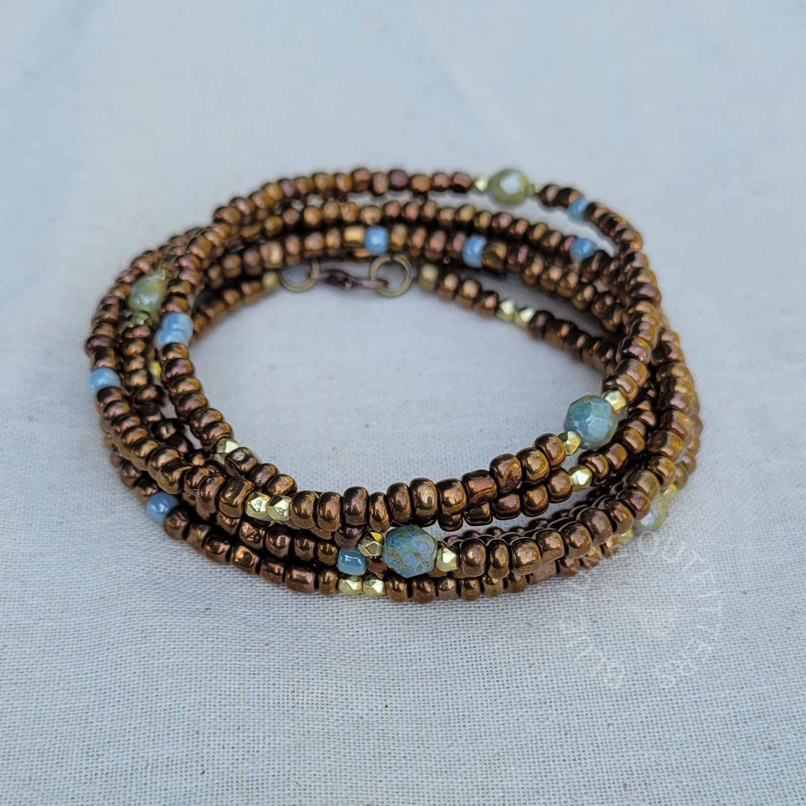 Close-up of boho wrap bracelet with brown, blue and gold glass beads wrapped 5 times - earthy statement jewelry