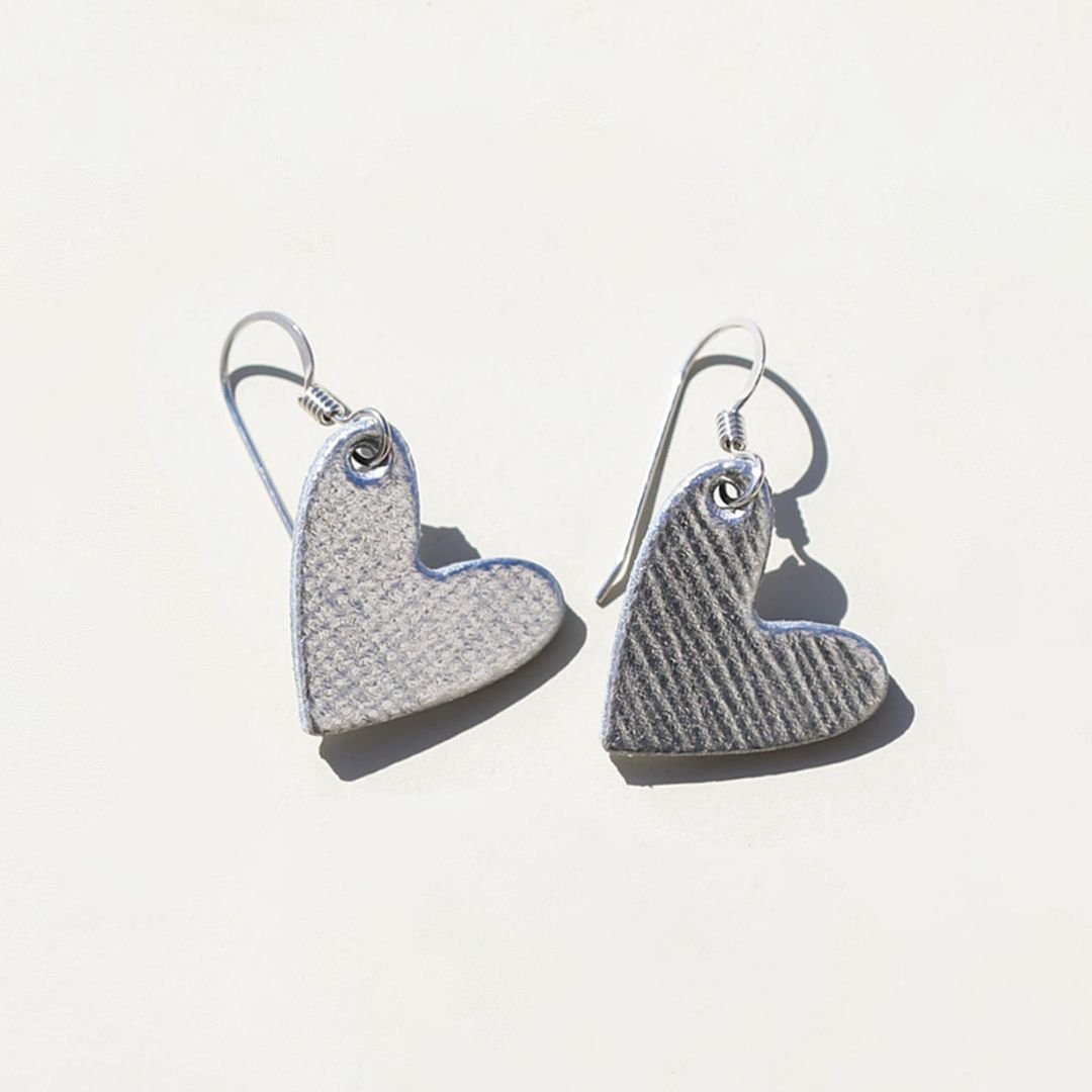 Heart-shaped silver earrings on a light gray background