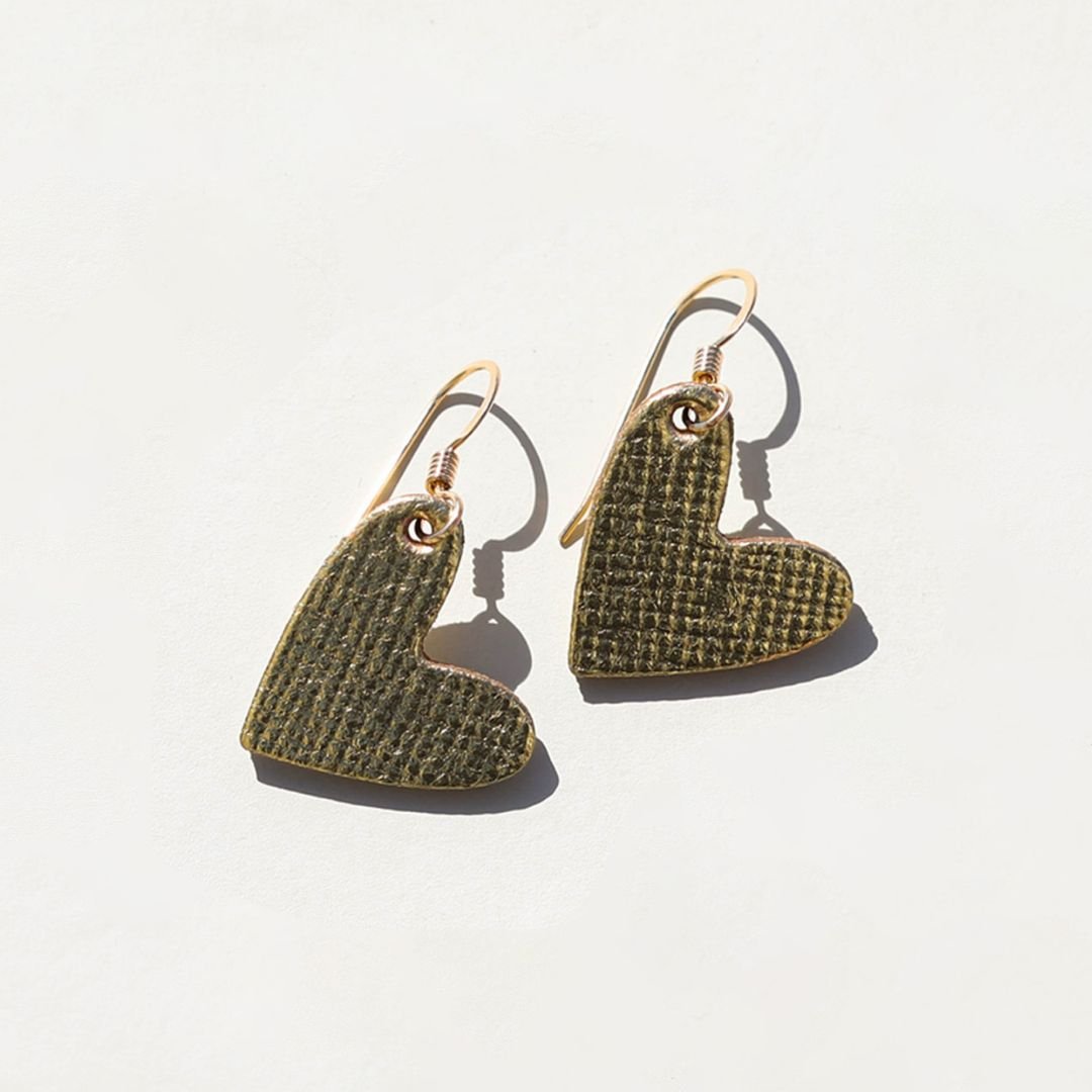 Heart-shaped gold earrings with textured design on a light background