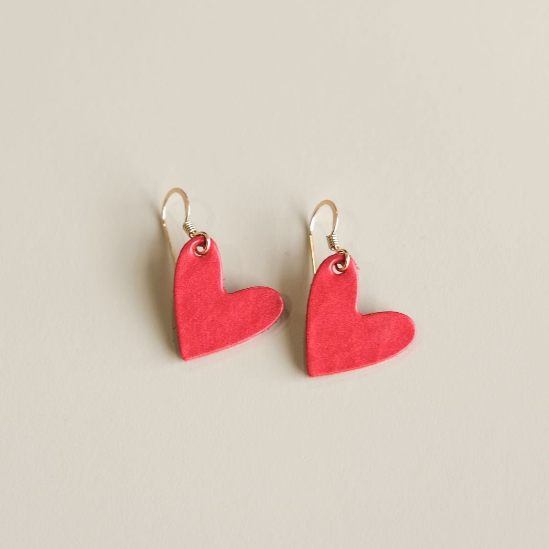 Red heart-shaped earrings on a beige background