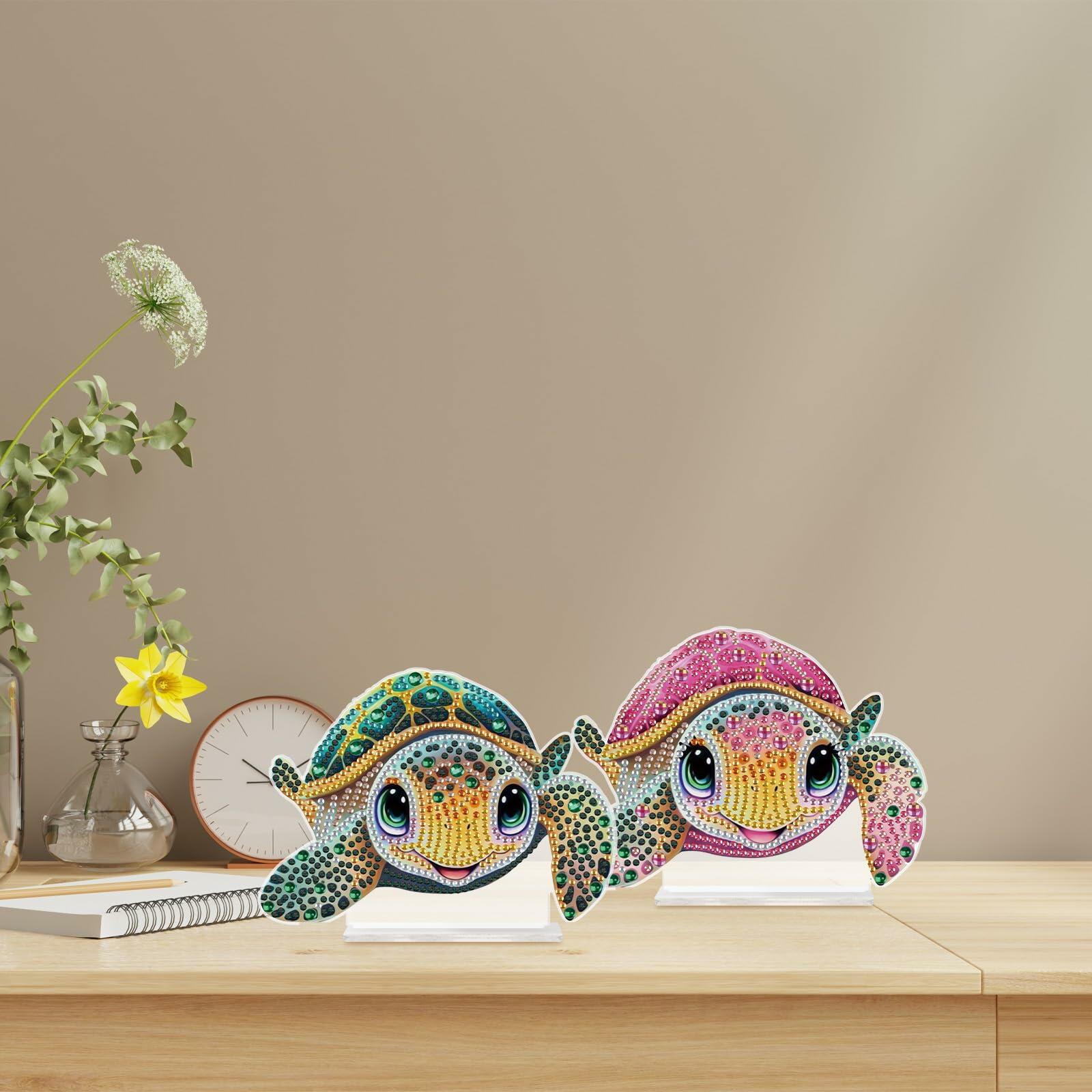 Two colorful diamond art turtle figurines on a wooden surface with a neutral background