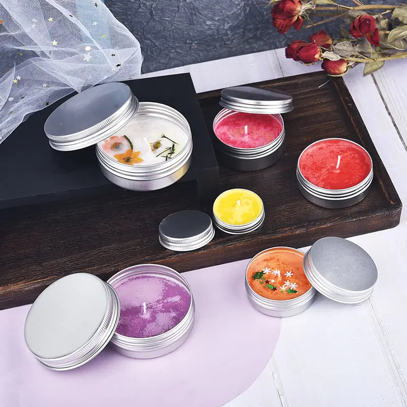 Set of small colorful wax filled candles with lids in metal containers on wooden tray