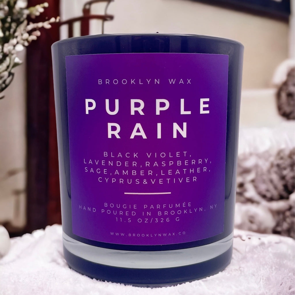 Purple Rain candle by Brooklyn Wax on white surface with plants in background