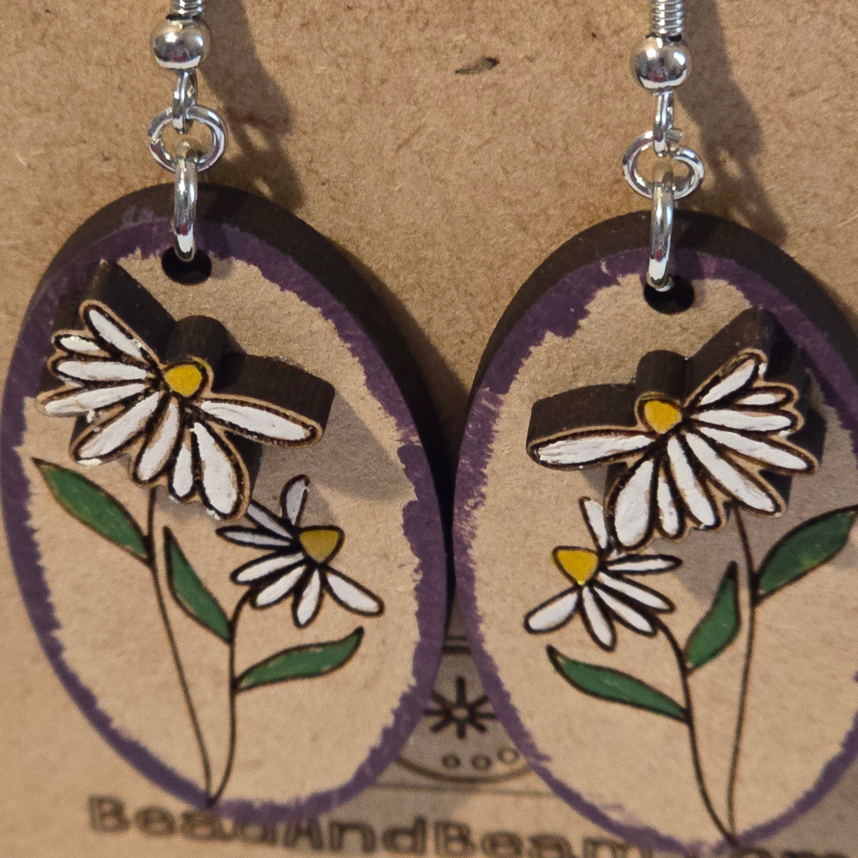 Top view of hand-painted daisy oval earrings showing 3D floral detail on rustic wood background - handmade dangle earrings