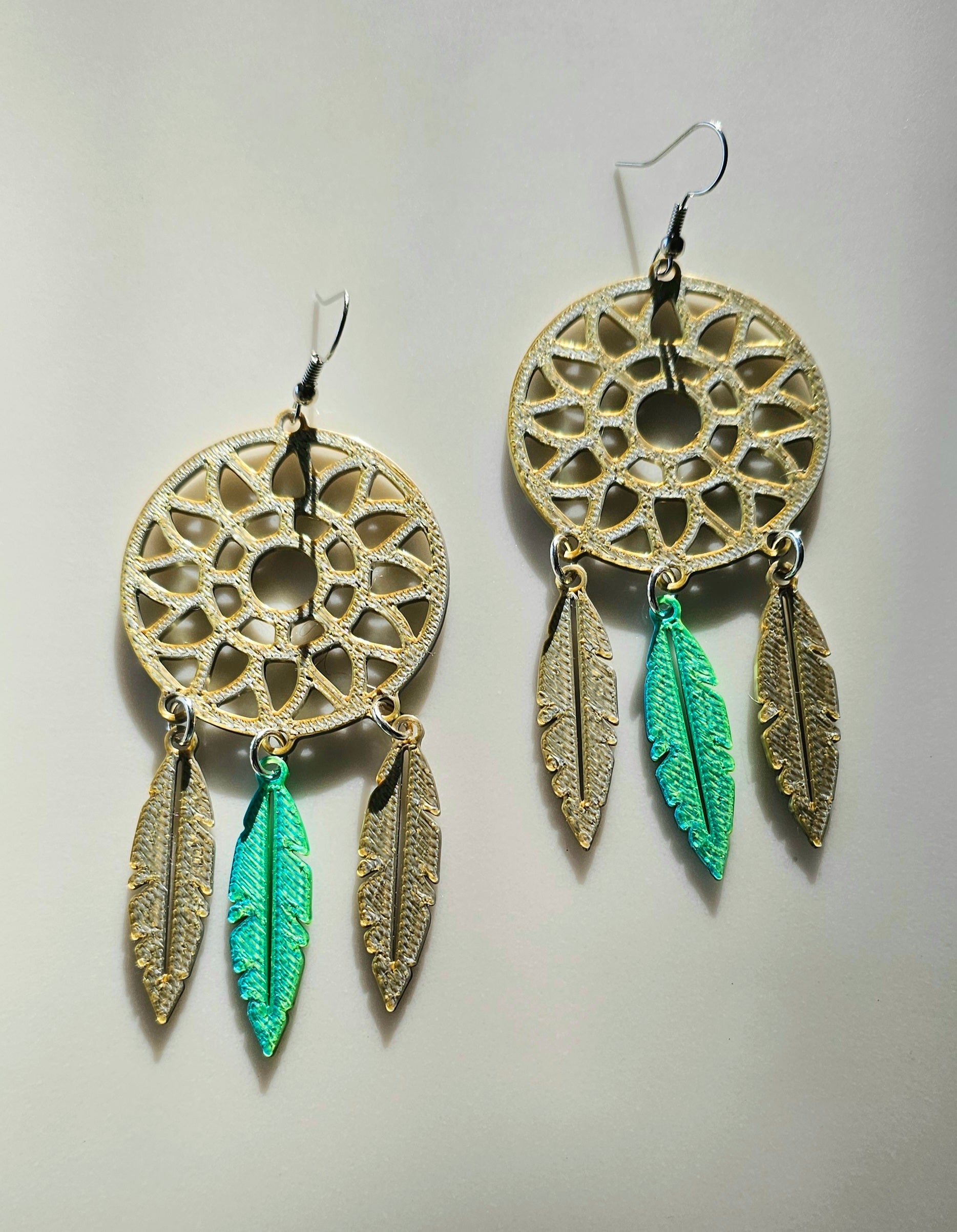 Gold dreamcatcher earrings with gold and green feather charms on light gray background - 3D printed ultra lightweight
