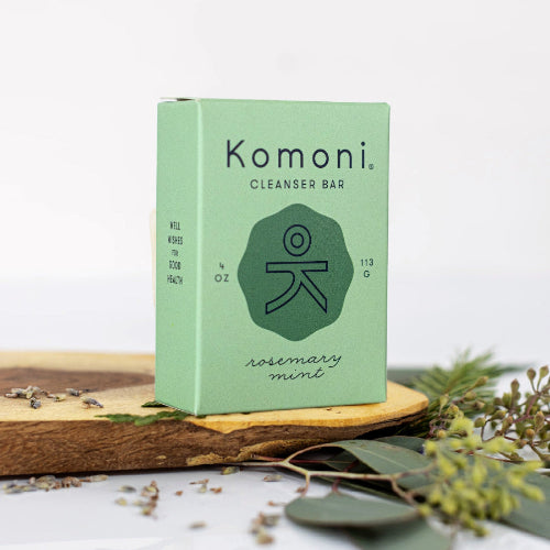 Rosemary mint face and body cleansing bar - KOMONI natural soap green box on wooden slab with plants