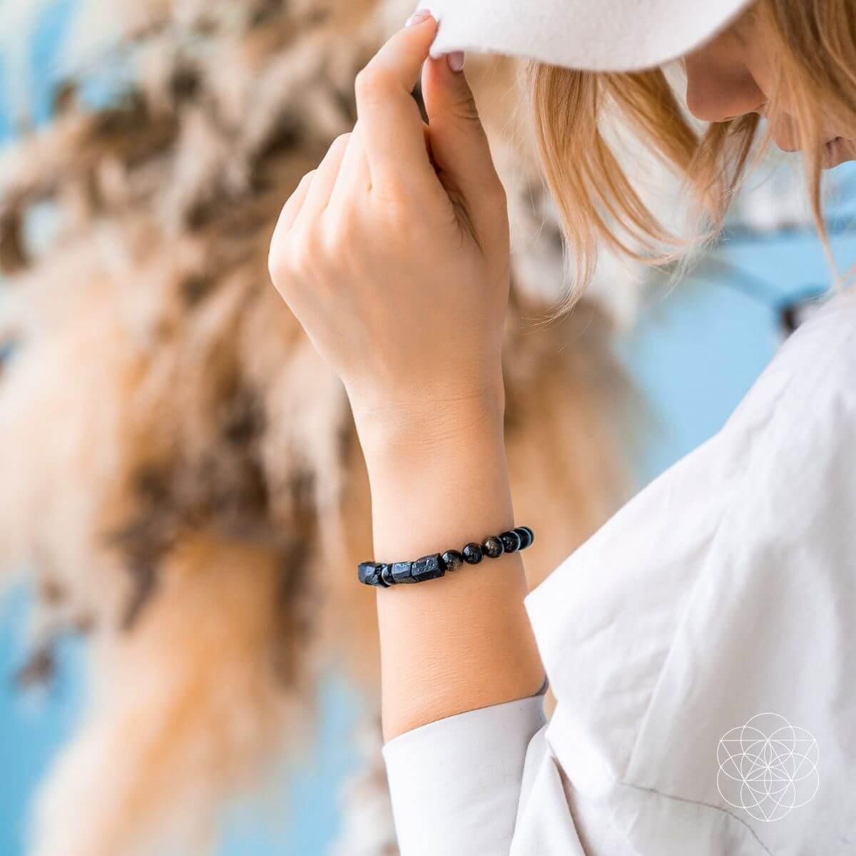 Person wearing black beaded spiritual protection bracelet outdoors - sacred crystal energy jewelry