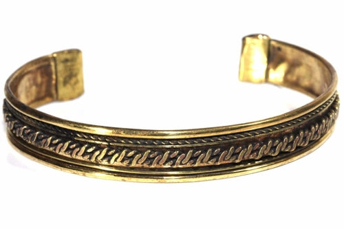 Close-up of tribal brass bangle showing detailed ethnic patterns - statement jewelry